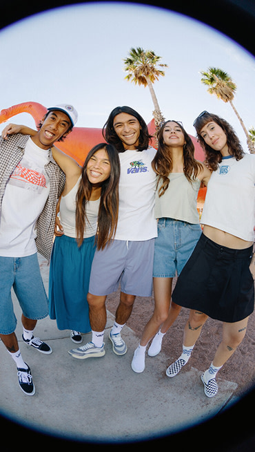 A fisheye image of a group of friends under palm trees wearing Vans shoes and clothes for spring break.