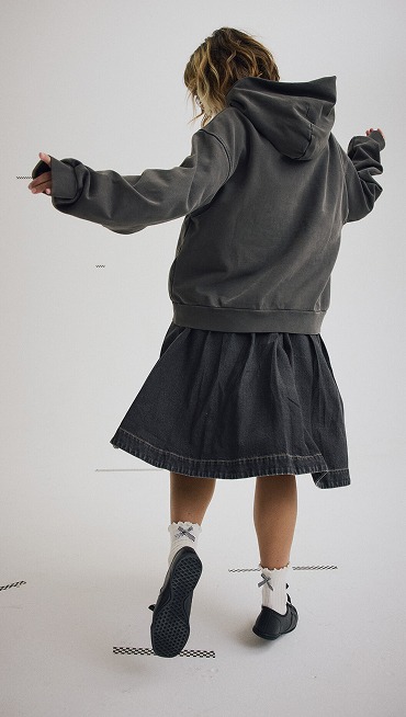 A young woman twirling in a photography studio wearing a denim Francesca Full Skirt and a faded black Premium Pullover Hoodie.