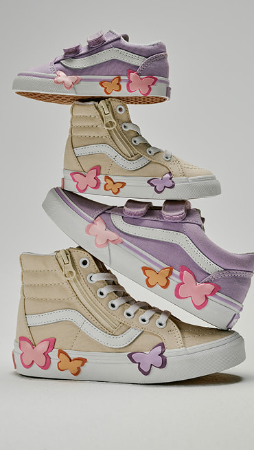 Various kids’ sizes of the Old Skool V and the Sk8-Hi Side Zip with butterfly details stacked on each other in a photography studio.
