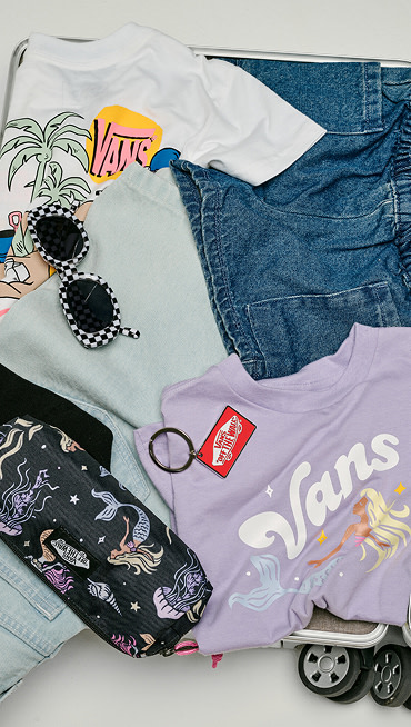 A variety of tees, boardshorts, socks, and Vans shoes in a rolling suitcase for spring break.