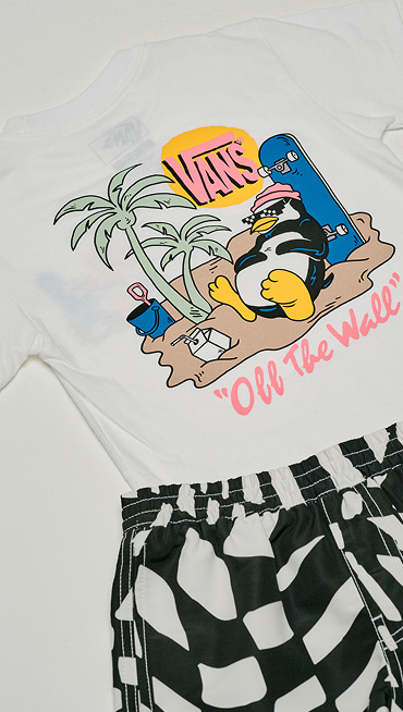 A Little Kids Yolo Penguin T-Shirt and Kids Primary II Printed Elastic Boardshorts on the floor of a photography studio.