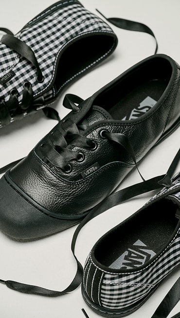 The black and white Checkerboard colorway and the black leather colorway of the Premium Authentic Prima on the floor of a photography studio.