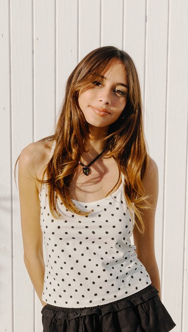 Vans Surf Team Rider Maddie Miller smiling at the camera wearing a white and black polka dot Cross Back Tank Top.
