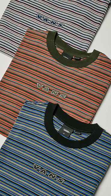 Three colorways of the Cameron Stripe Knit Shirt folded and stacked on top of each other on the floor of a photography studio.