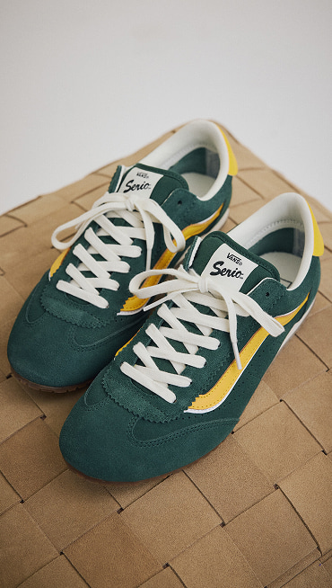 Close-up on a pair of green and yellow Super Lowpro shoes on top of an ottoman in a photography studio.