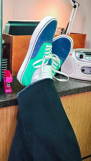 Close-up of a man putting his feet on a desk in the navy and green Authentic shoes from the Worn Loud Authentic Legacy drop.