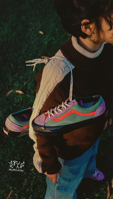 Image of a girl standing in a field with the OTW x Julian Klincewicz shoes hanging over her shoulder by the laces. 
