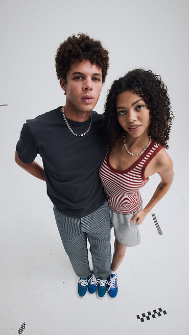 A young man and woman standing together with the shoes alternating wearing blue Authentic shoes and red and blue Super Lowpro.