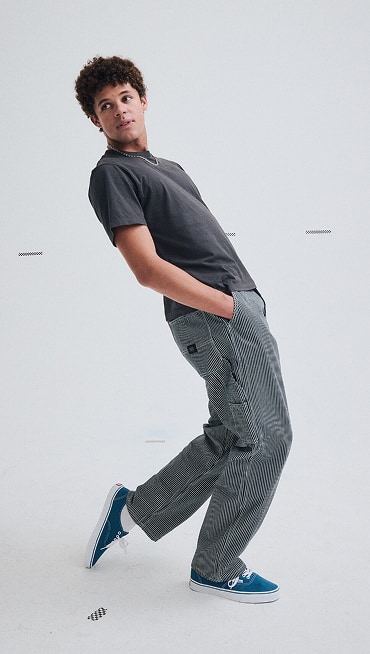A young man posing in a photography studio wearing blue gray Drill Chore Carpenter Loose Pants.