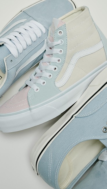 Close up shot of the Old Skool, Sk8-Hi, and Authentic in light blue colorways laying on the floor of a grey photography studio.