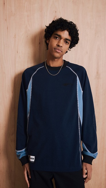 A waist-up shot of a young man wearing a dress blues Retro Sport Long Sleeve T-Shirt.