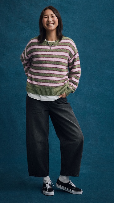A young woman poses against a picture day backdrop in Vans shoes and clothes for Back to School.