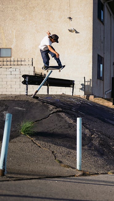 Extreme wide shot of Nick Michele from the Vans Skate Team grinding down a small rain on top of a concrete hill.