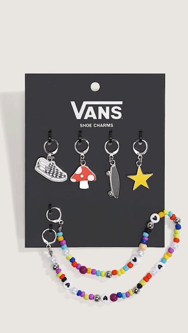 A set of Vans shoe charms including a mushroom, skateboard, star, and beaded bracelet in a photography studio.