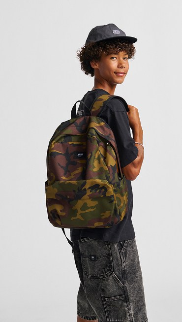 A boy poses with an Old Skool Camo Backpack in a photography studio.