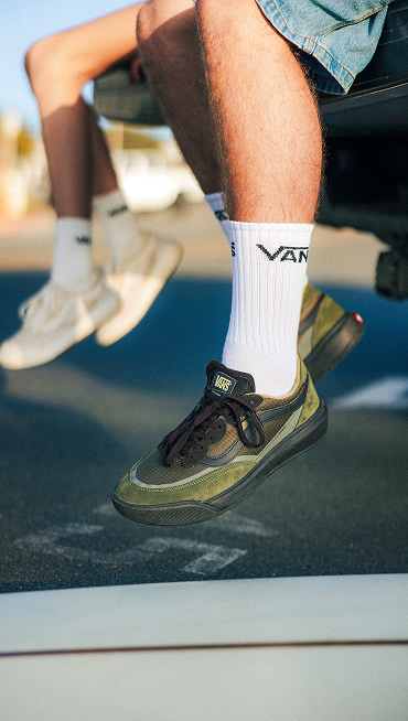 A man and woman sit on the bed of a truck, their feet dangling and wearing UltraRange 2.0.