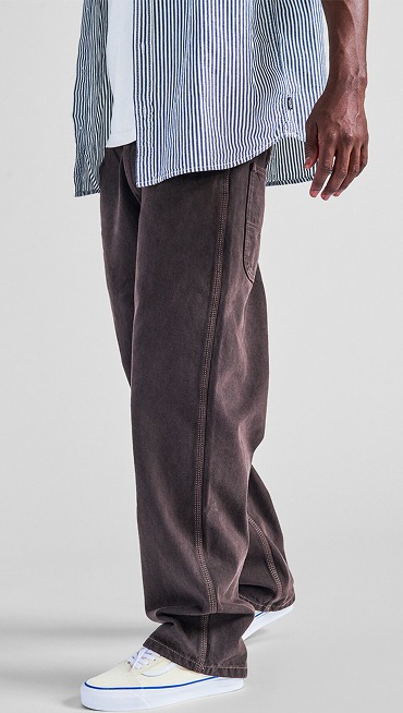 A waist-down shot of a man wearing a blue and white Lawson Stripe Button Up Shirt, brown jeans, and white and blue Premium Authentic.
