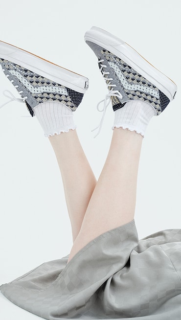 A person throws their Premium Old Skool shoes in the air while on their stomach in a photography studio.