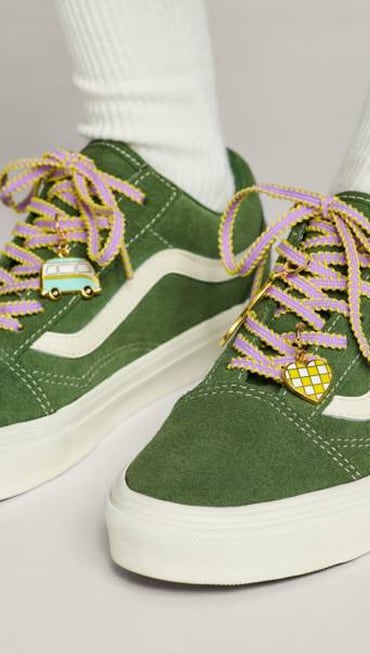 Close-up of some laces and charms on a green Old Skool shoe.
