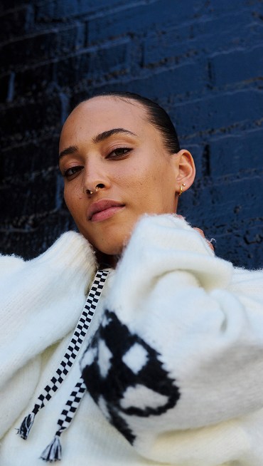 A woman looks into the camera wearing a white vans hoodie with Checkerboard drawstrings.