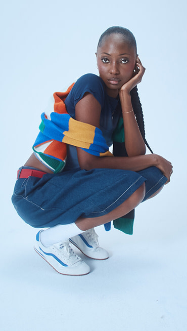 Musician Vanessa squats and poses wearing white and true blue Super Lowpro with denim shorts on the set of Open Set Los Angeles.