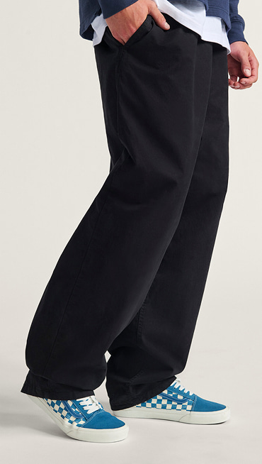 A knee-down shot of a man wearing blue Checkerboard Premium Old Skool paired with black Authentic Chino Relaxed Pants.