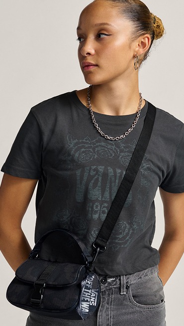 A young woman poses in a photography studio wearing a Hooked On Mini Bag in black camo.