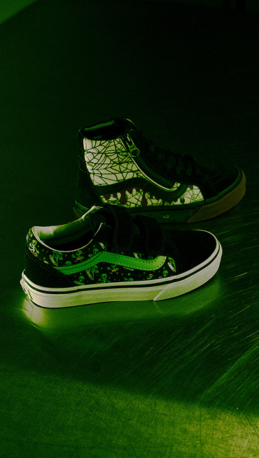 Glow-in-the-dark Sk8-Hi and Old Skool illuminate a dark room with a green tint.