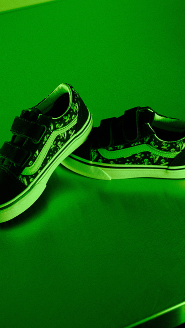 A close-up on kids’ glow-in-the-dark velcro Old Skool with an alien pattern in neon green light.