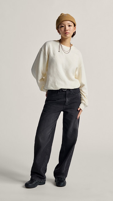 A young woman poses for the camera in a photography studio wearing a white Navigate Long Sleeve Thermal with black Sirelle 5 Pocket Puddle Pants.