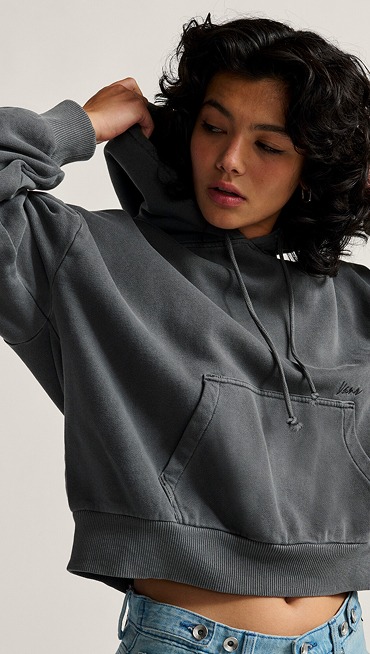 A young woman pulls the hood up on an asphalt gray Retro PO Hoodie in a photography studio.