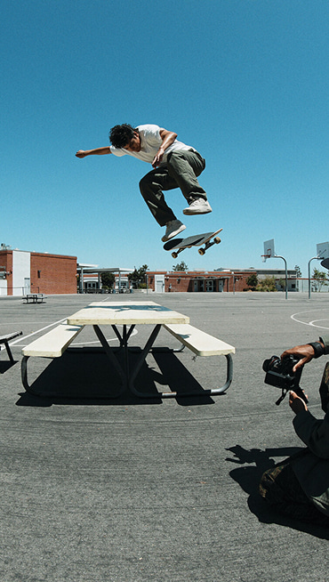 Vans Skate Team Rider Nick Michel jumping off a playground table wearing white Skate Half Cab from the United Through Skateboarding collection.