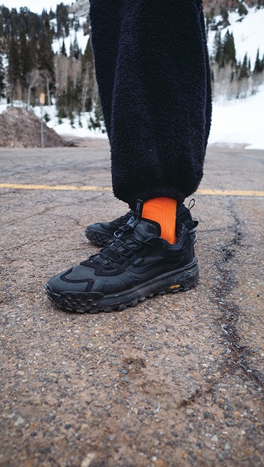 A waist-down shot of someone wearing black Crosspath XC GORE-TEX with fleece pants in the parking lot of a ski resort.