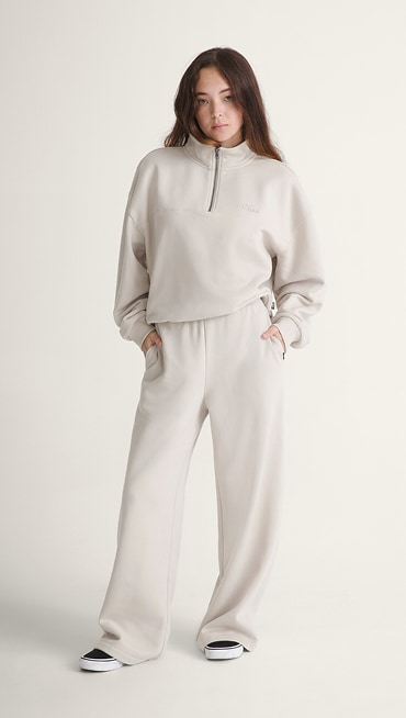 A young woman poses in a photography studio wearing white Drop V Sweatpants.