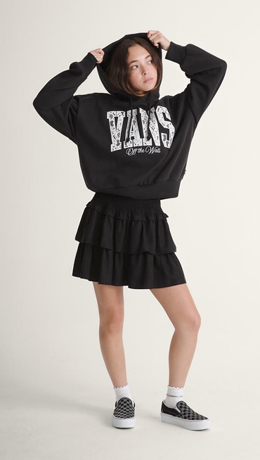 A young woman poses in a photography studio wearing a black Ava Tiered Mini Skirt.