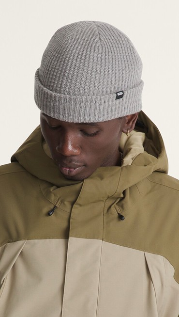 A young man wearing a gray Core Basic Cuff Beanie checks the fit of his Vans raincoat in a photography studio.