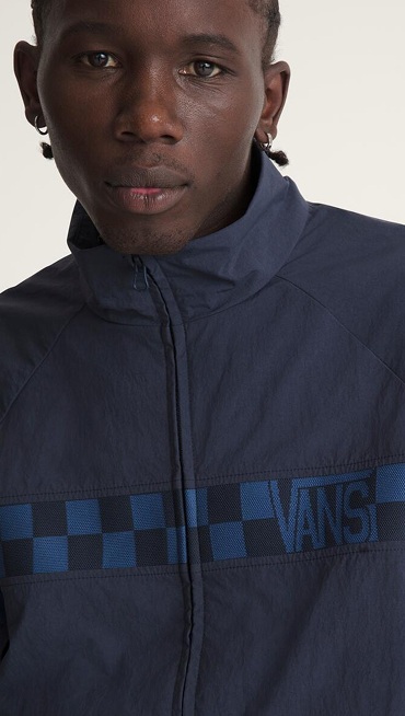 A close-up of a young man wearing a navy Ronnie Track Jacket in a photography studio.