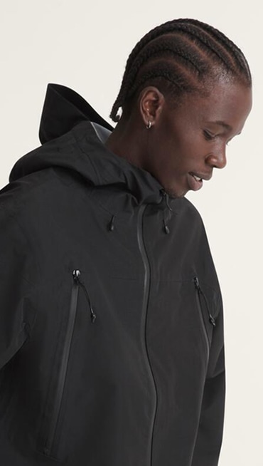 A waist-up shot of a young man wearing a black Hi-Country Snow Jacket in a photography studio.