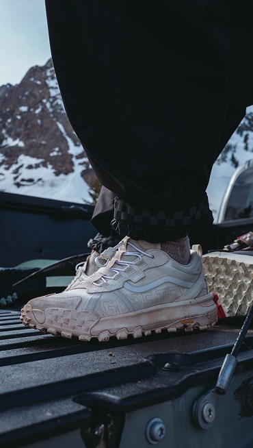 Close-up on the white Crosspath XC GORE-TEX in the bed of a truck with snowboarding gear and a mountain in the background.