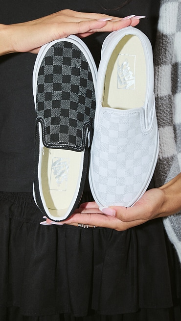 A woman holds up the metallic Classic Slip-On Platform Checkerboard.