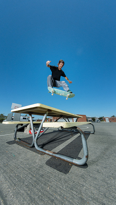 Vans Skate Team Rider Geoff Rowley jumping over a table wearing Skate Curren Caples from the United Through Skateboarding collection.