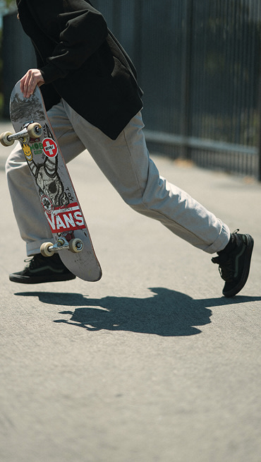A waist-down shot of someone running to jump on their board wearing black The Skate Old Skool™ 36+.