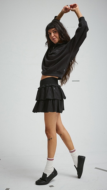 A young woman wearing black Skate Loafers and a black skirt in a photography studio.