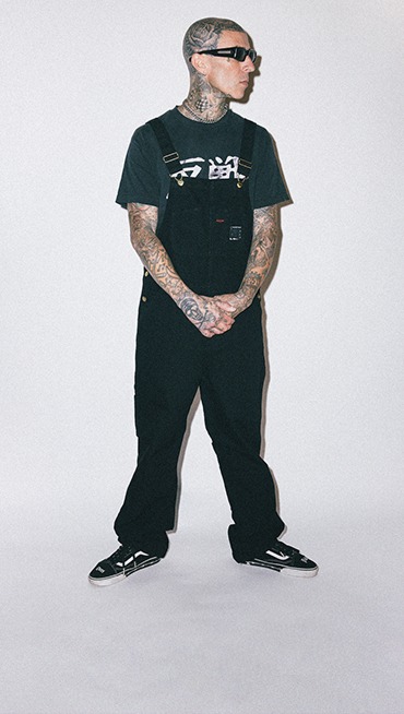 A waist-down shot of Travis Barker wearing the Vans x Travis Barker Old Skool with the Dues Paid emblem.