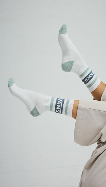 Close-up on white Vans crew socks in the air as someone lays on their back in a photography studio.