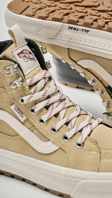 Close-up of someone wearing tan Sk8-Hi Insulated shoes with black jeans and white Vans crew socks.