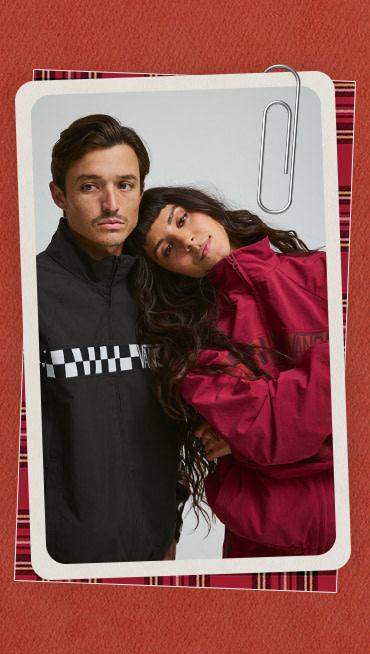 A photograph surrounded by a plaid holiday border of a young man and woman posing together in red and black Ronnie track jackets.