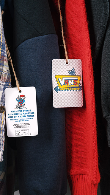 Close-up on a tag that read Vans Waffle Shop and another that reads Archival Prints, Reimagined Classics, and One of a Kind Pieces on Vans clothes.