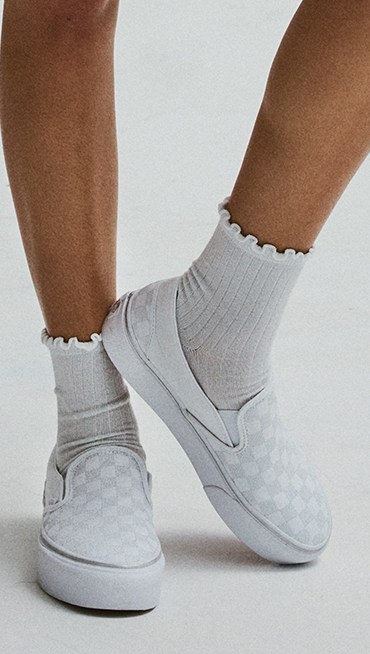 Close-up on the white and gray Classic Slip-On Platform Checkerboard with white frill socks.