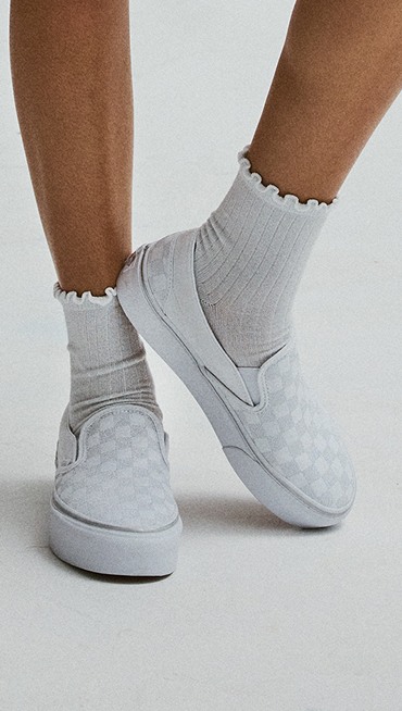 Close-up on the white and gray Classic Slip-On Platform Checkerboard with white frill socks.